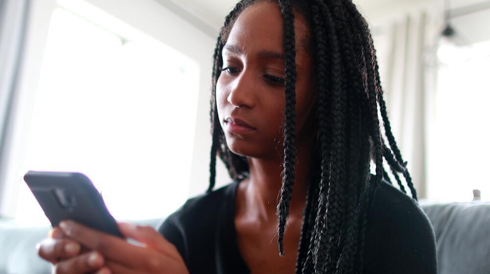 A young girl looks at her mobile phone. 